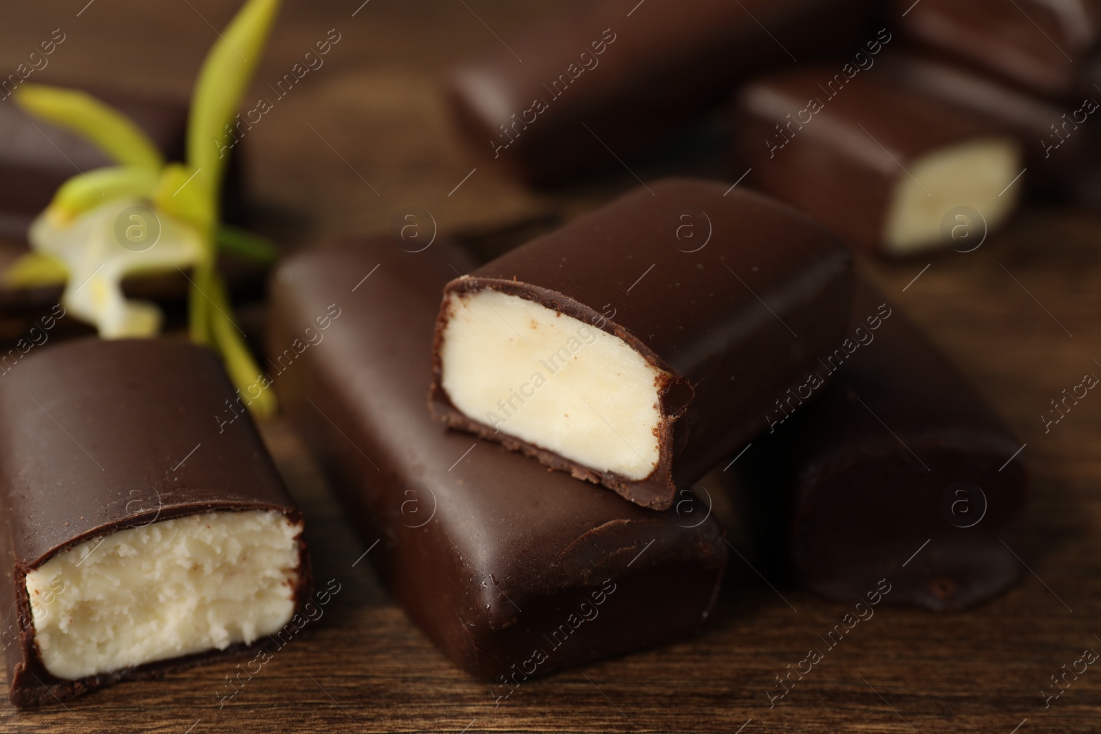 Photo of Glazed curd cheese bars on wooden table, closeup