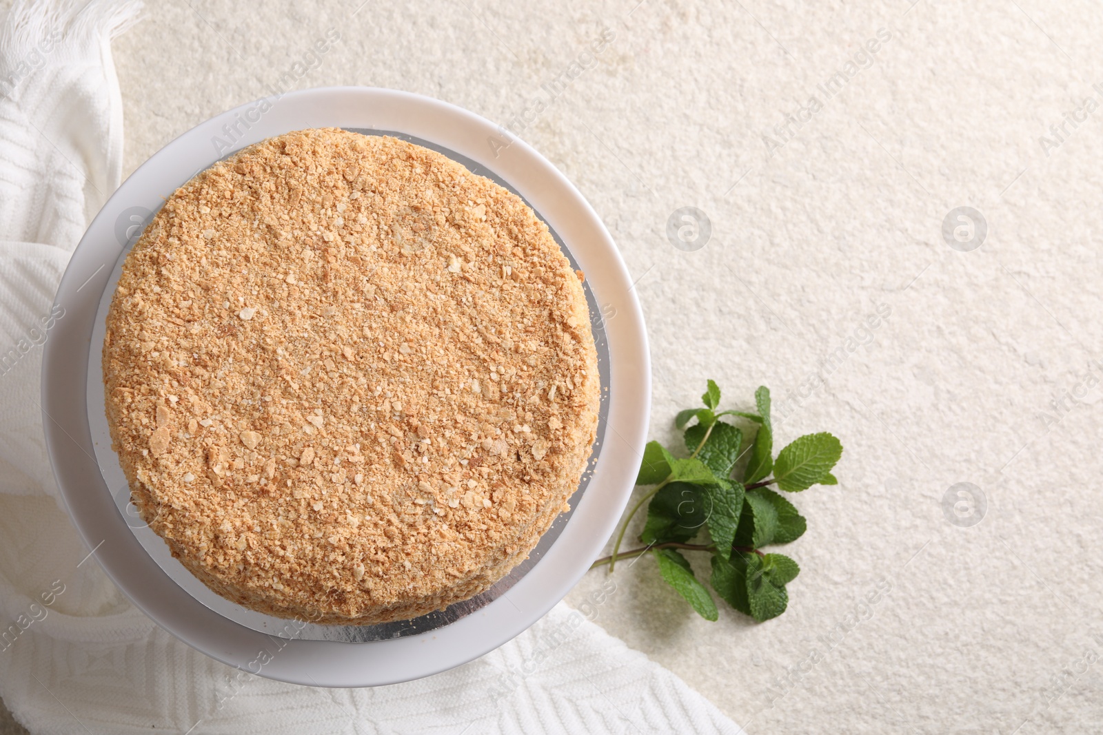 Photo of Delicious Napoleon cake and mint on beige table, flat lay. Space for text