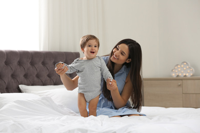 Photo of Young nanny with cute little baby in bedroom