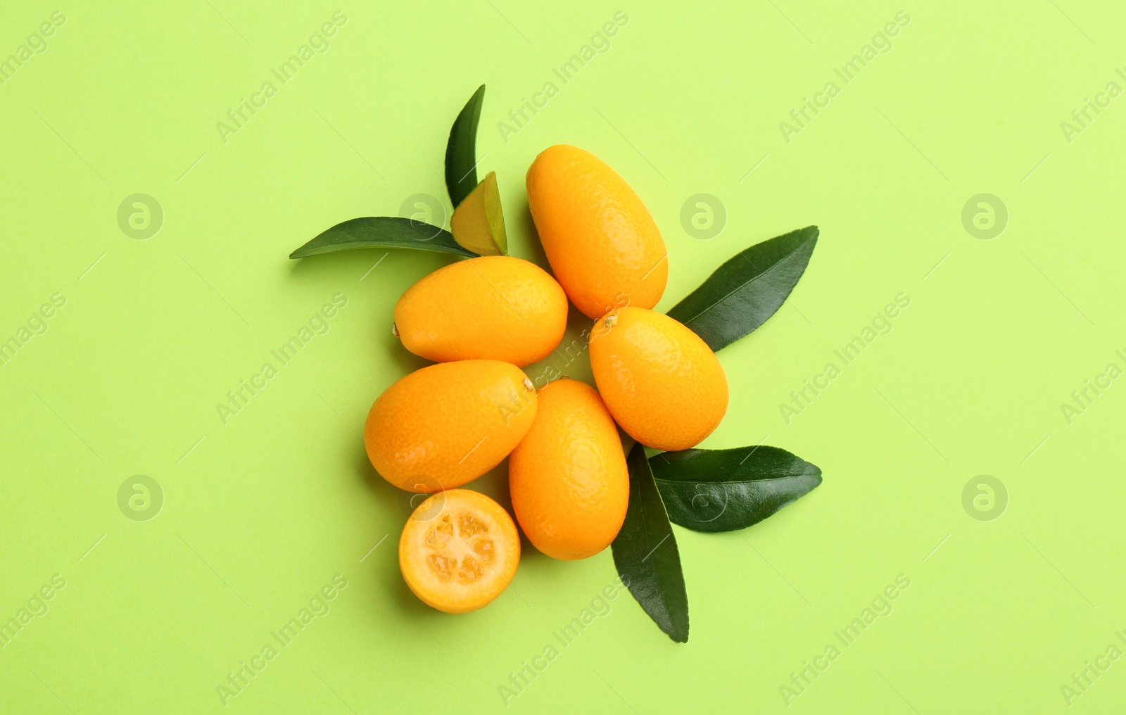 Photo of Fresh ripe kumquats on light green background, flat lay