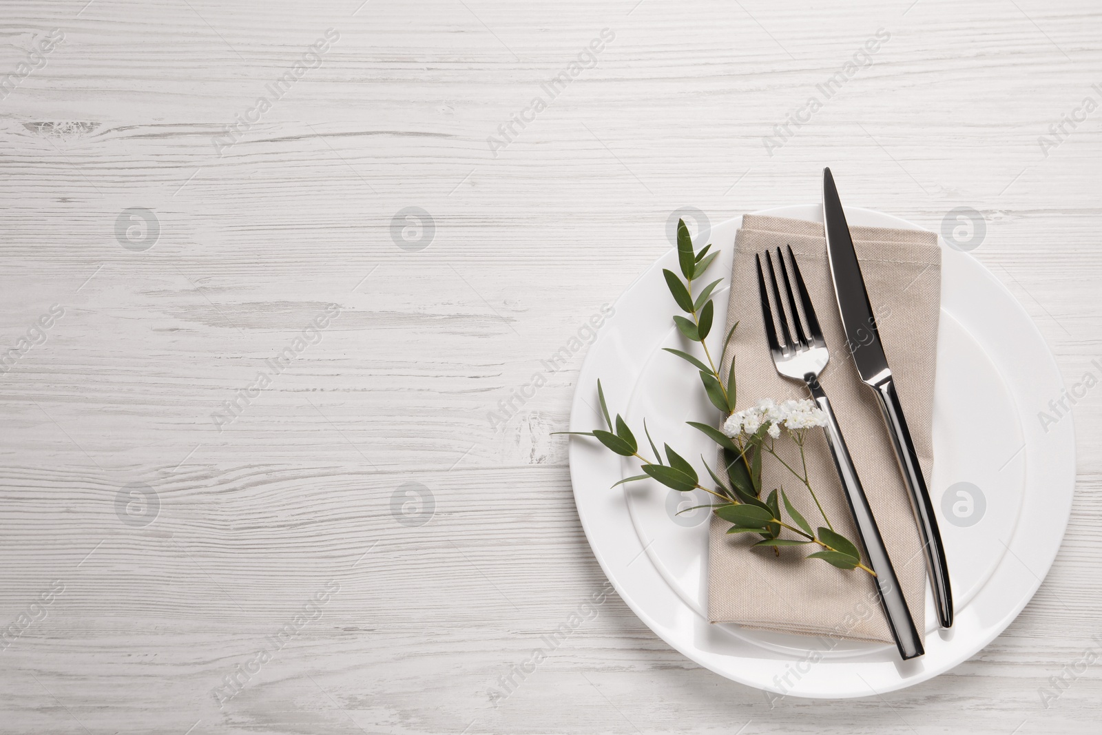 Photo of Stylish setting with cutlery and eucalyptus leaves on white wooden table, flat lay. Space for text