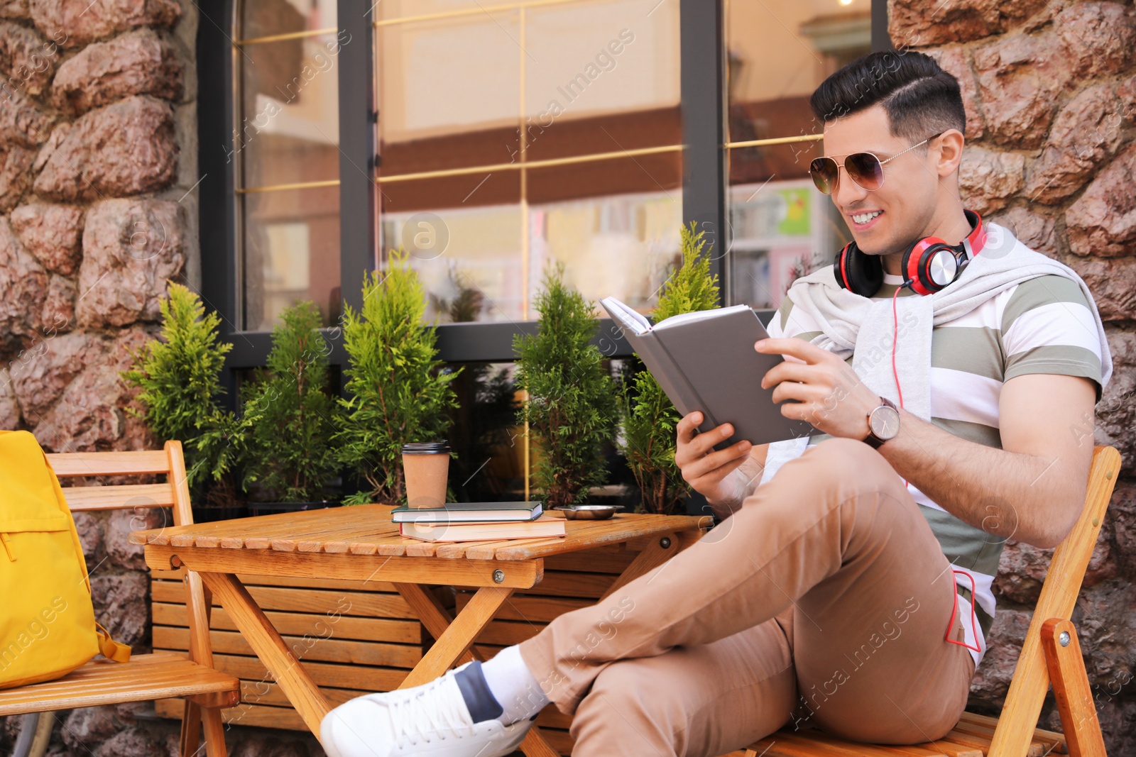 Photo of Handsome man reading book in outdoor cafe