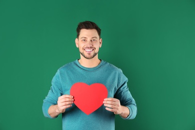 Portrait of handsome man with decorative heart on color background