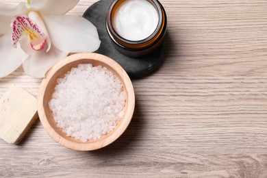 Flat lay composition with spa products and beautiful flower on light wooden table. Space for text