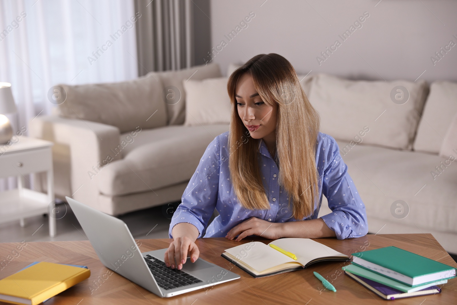 Photo of Young woman watching webinar at table in room