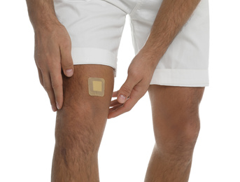 Photo of Man with sticking plaster on knee against white background, closeup