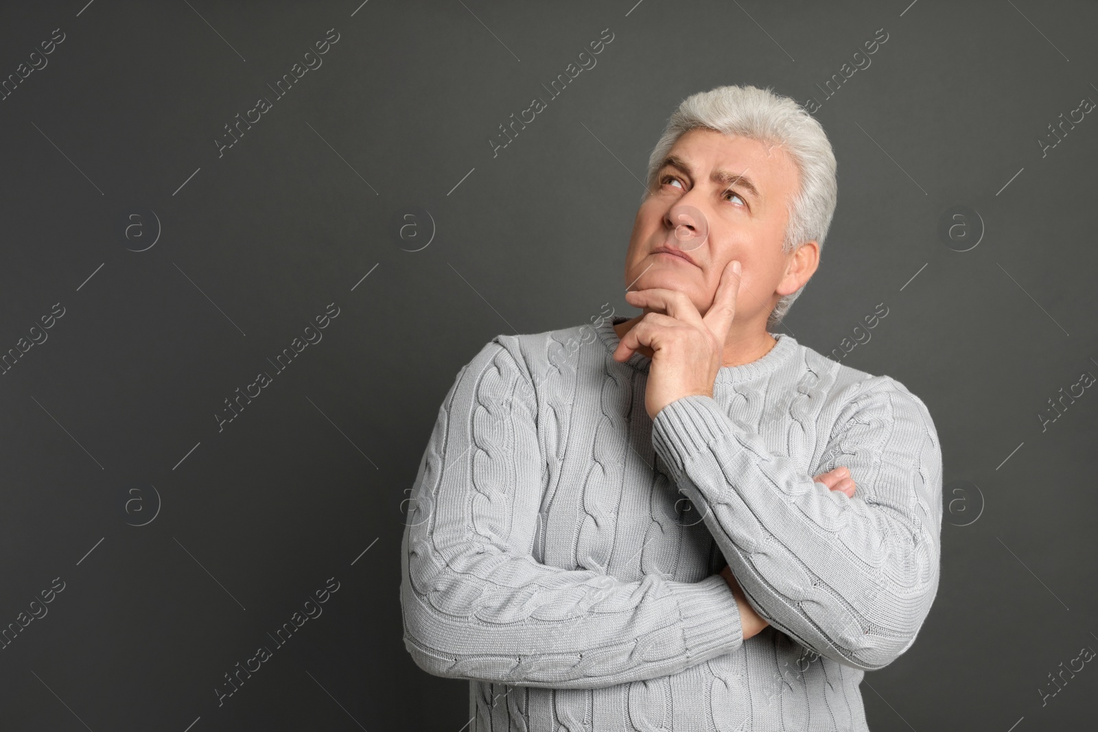 Photo of Thoughtful mature man on dark grey background