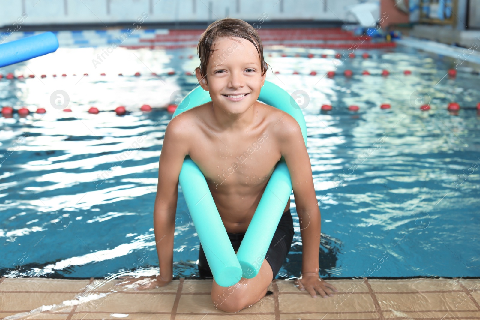 Photo of Little boy with swimming noodle in indoor pool