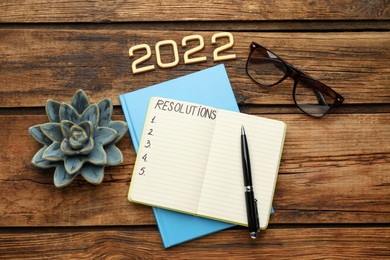 Photo of Making resolutions for 2022 New Year. Flat lay composition with notebook on wooden table