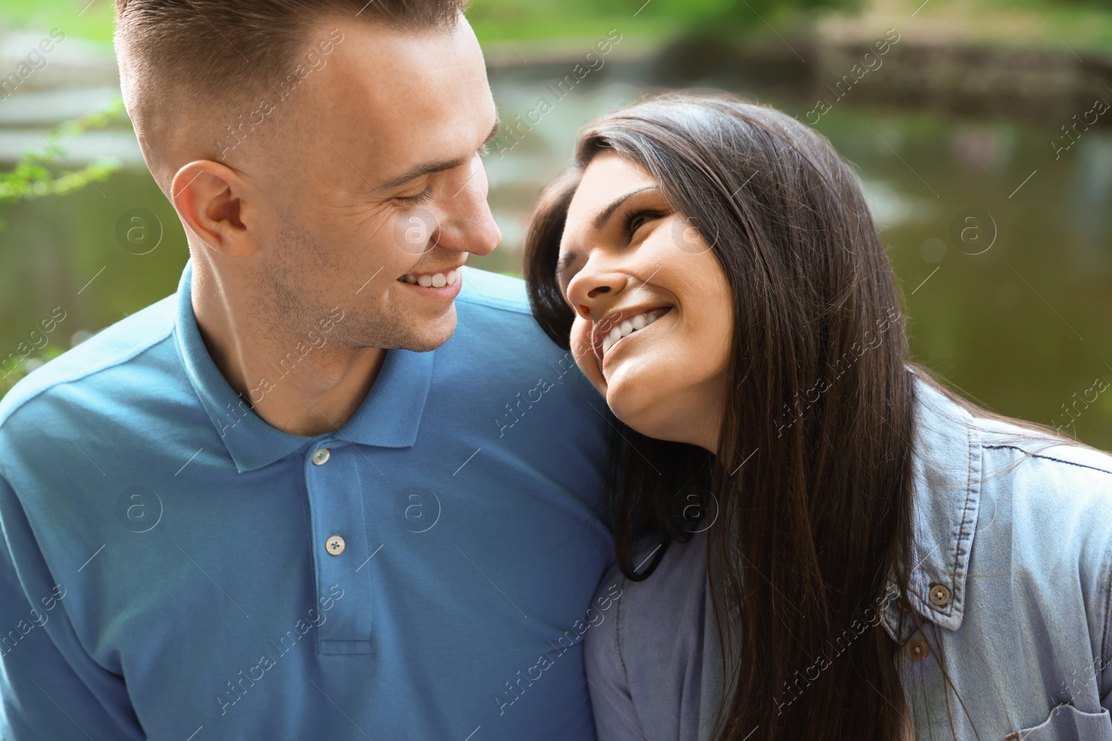 Photo of Affectionate young couple sitting together in park, closeup