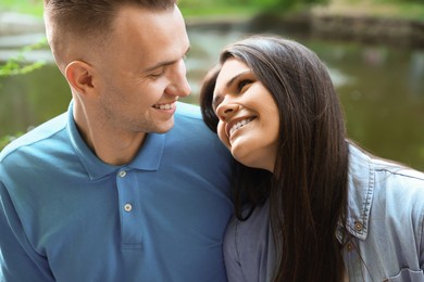 Photo of Affectionate young couple sitting together in park, closeup