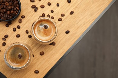 Photo of Tasty coffee and beans on wooden table, flat lay. Space for text