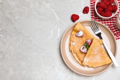 Photo of Delicious crepes served with mint, raspberries and powdered sugar on grey table, flat lay. Space for text