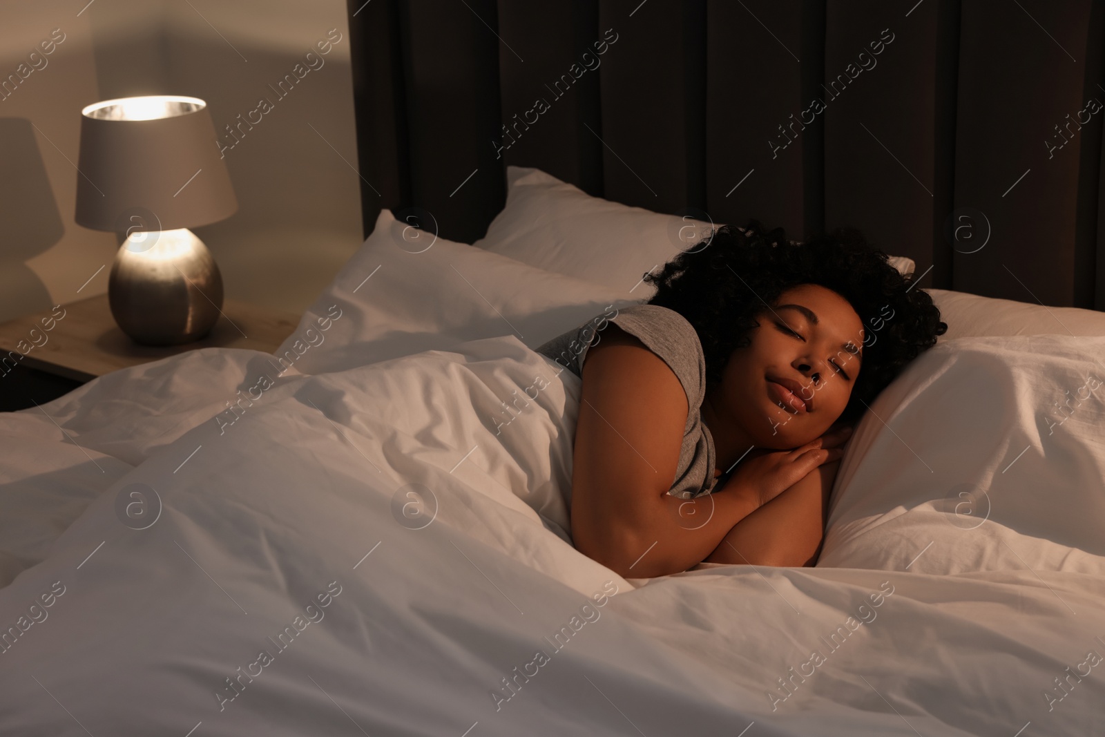 Photo of Young woman sleeping in soft bed at night