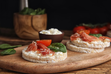 Photo of Puffed rice cakes with prosciutto, tomato and basil on wooden board