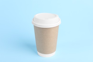 Paper cup with plastic lid on light blue background. Coffee to go