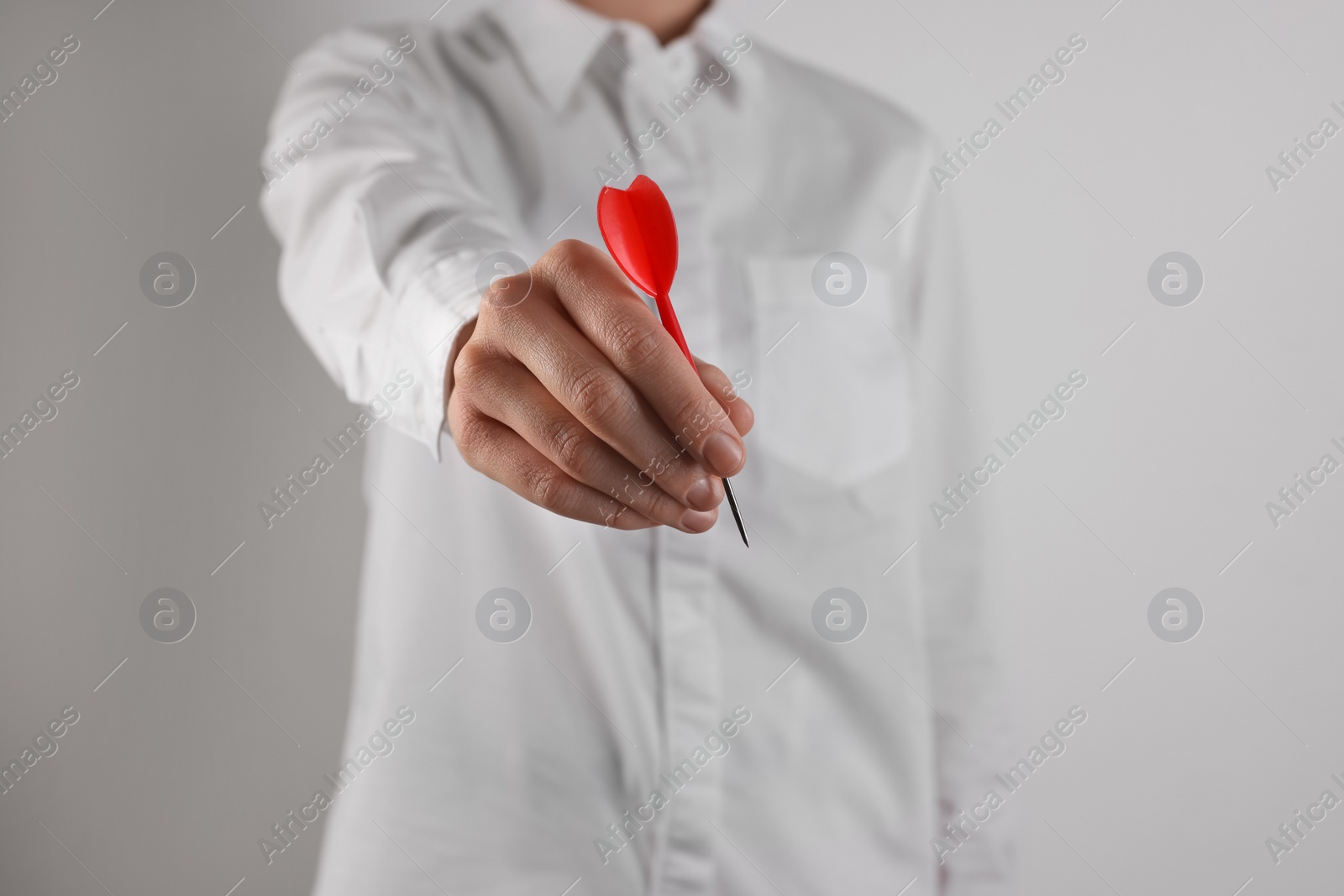 Photo of Businesswoman holding red dart on light background, closeup