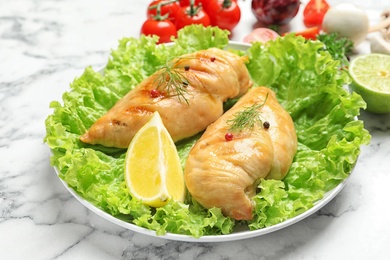 Plate with grilled chicken breasts and garnish on marble table