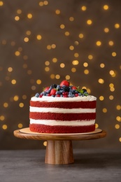 Stand with delicious homemade red velvet cake against blurred lights