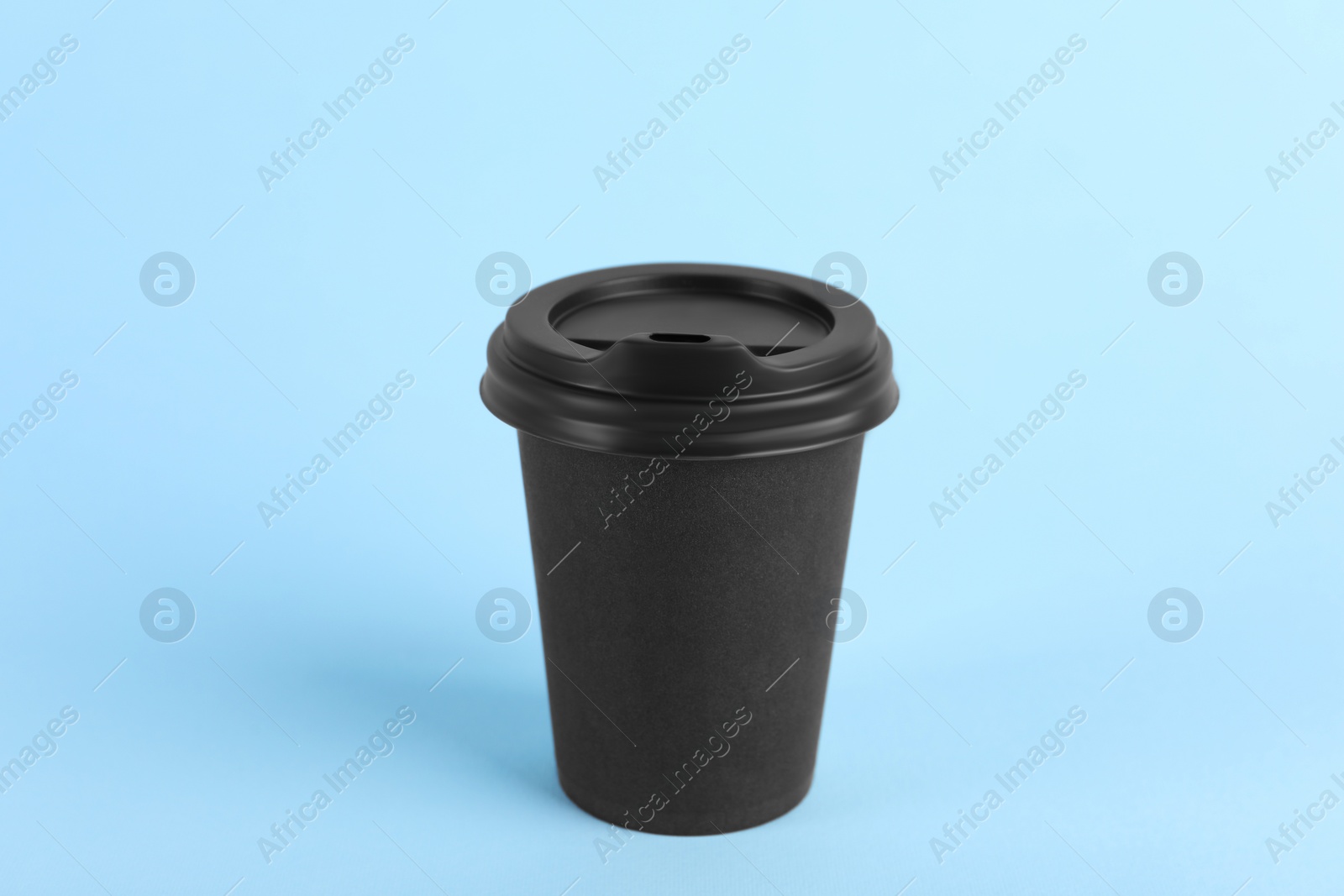 Photo of Black paper cup with plastic lid on light blue background. Coffee to go