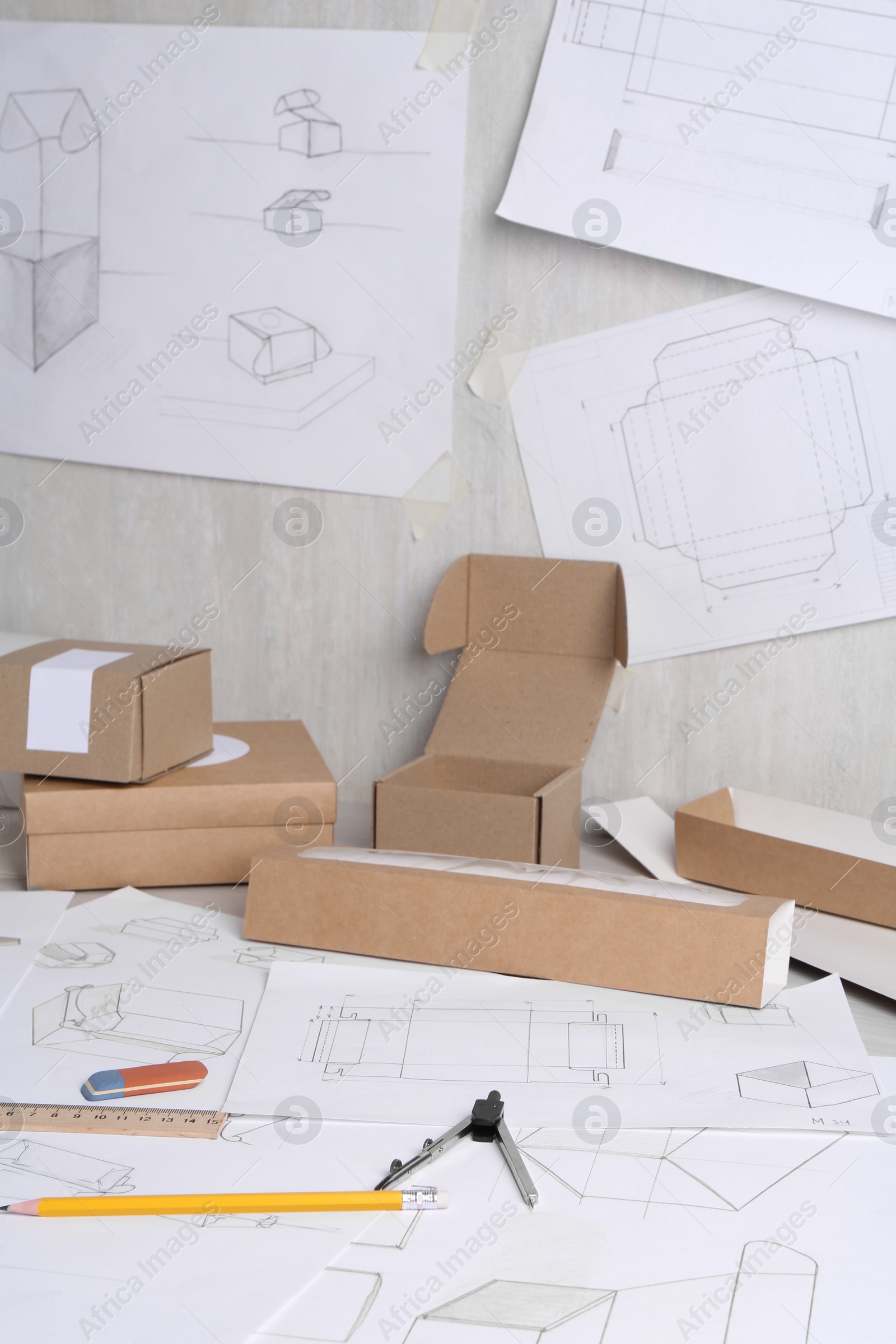 Photo of Creating packaging design. Drawings, boxes and stationery on table, closeup