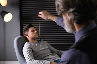 Photo of Psychotherapist using pendulum during hypnotherapy   session in office