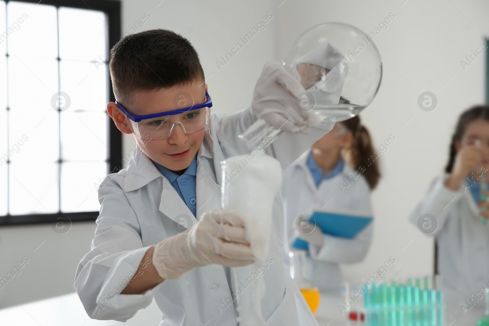 Photo of Smart schoolboy making experiment in chemistry class