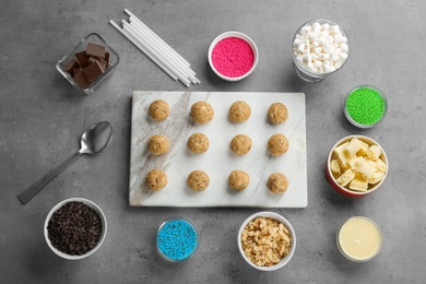 Flat lay composition with half made cake pops and ingredients on grey background