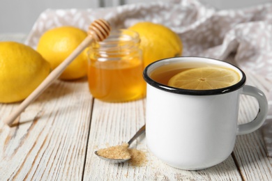 Photo of Cup with hot lemon tea on wooden table