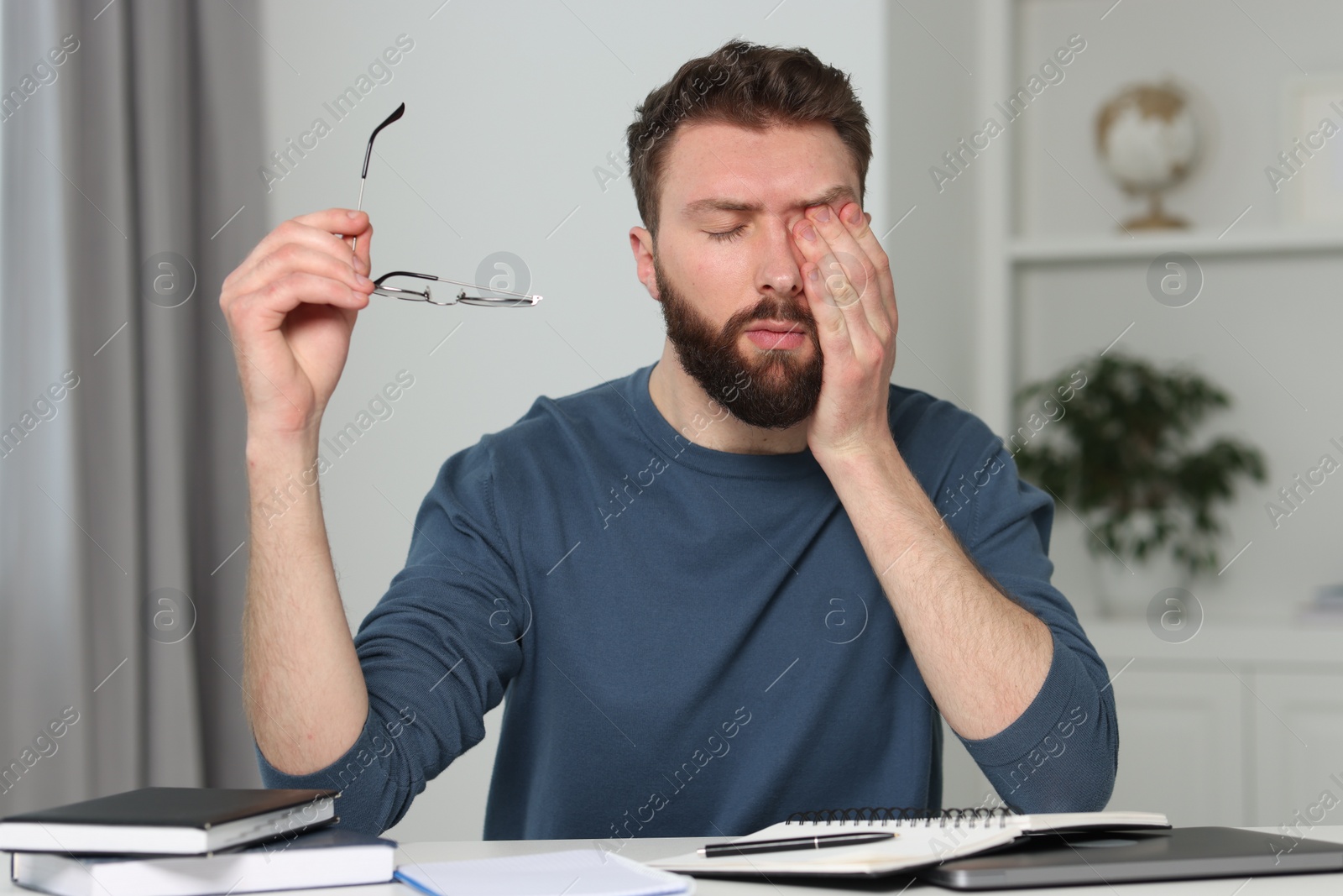 Photo of Overwhelmed man with glasses at table indoors