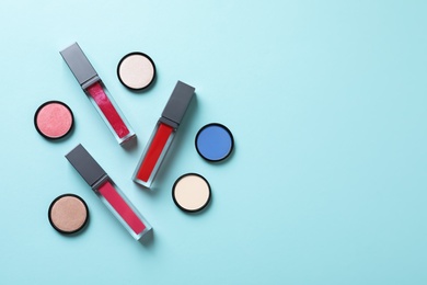 Photo of Composition of lipsticks and eyeshadows on color background, flat lay. Space for text