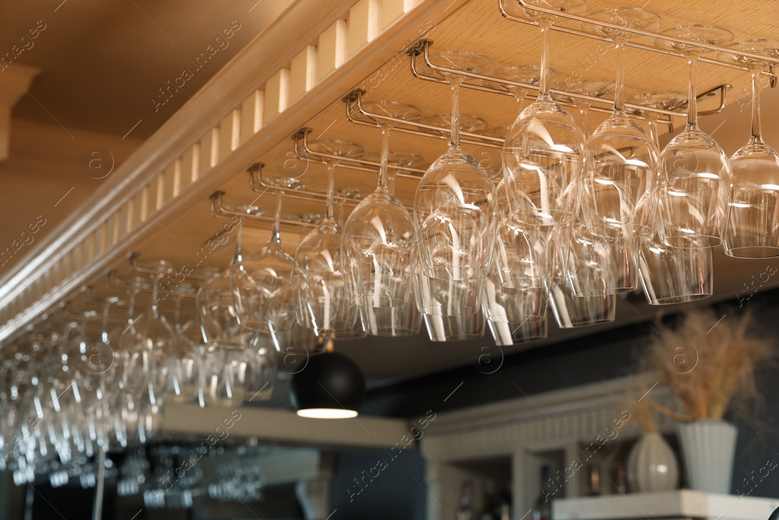 Photo of Set of empty clean glasses on bar racks