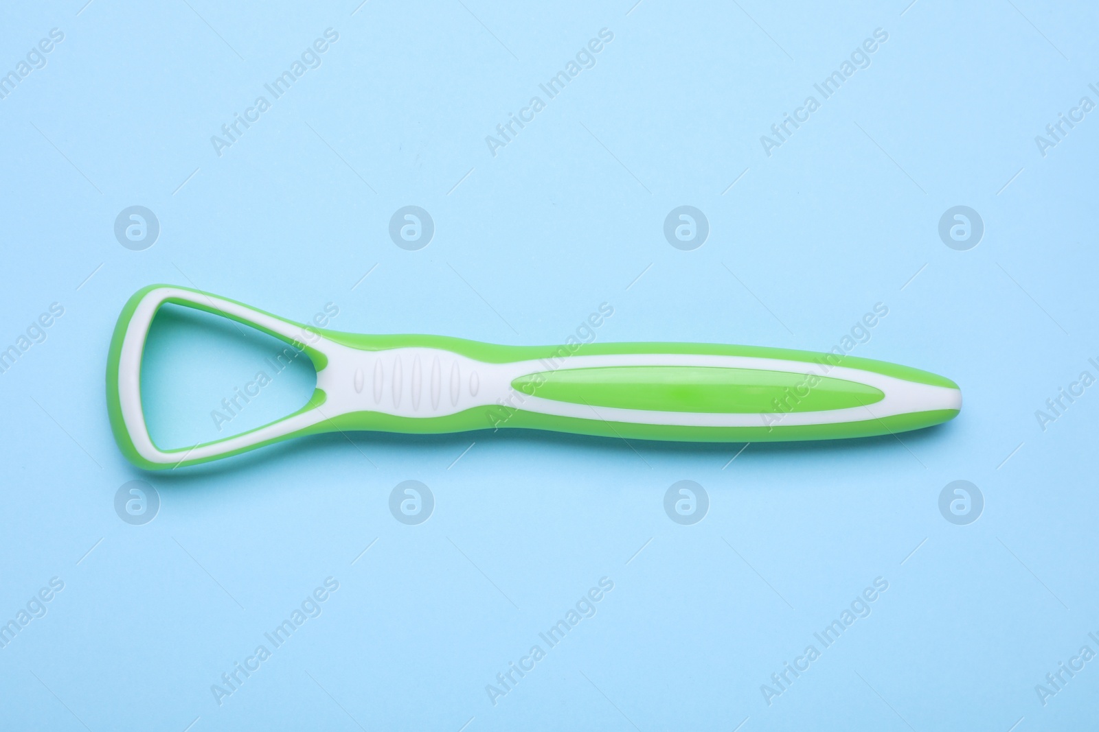 Photo of Green tongue cleaner on light blue background, top view