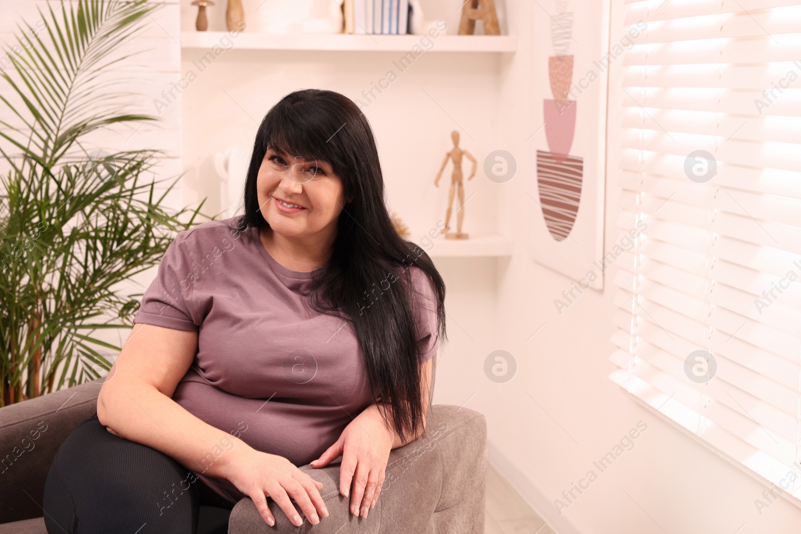 Photo of Beautiful overweight woman sitting in armchair at home