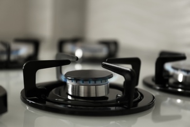 Gas burners with blue flame on modern stove, closeup