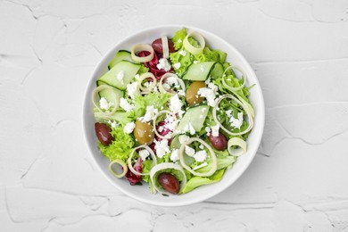 Photo of Bowl of tasty salad with leek, olives and cheese on white textured table, top view