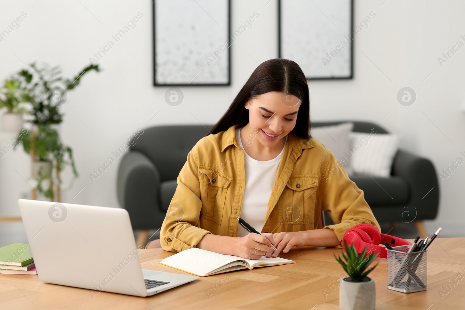 Photo of Online translation course. Student writing near laptop at home