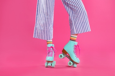 Photo of Young woman with retro roller skates on color background, closeup