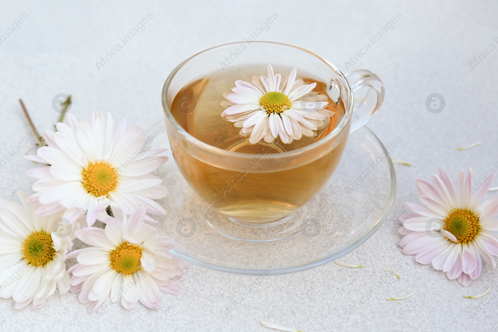 Photo of Glass cup of delicious chamomile tea on white table