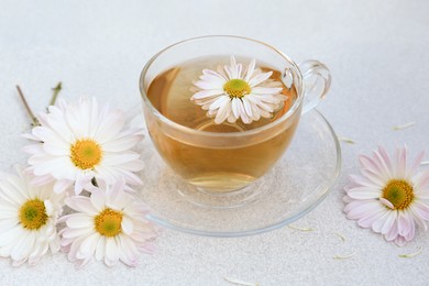 Photo of Glass cup of delicious chamomile tea on white table