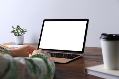 Photo of Woman working on laptop at wooden table, closeup. Mockup for design