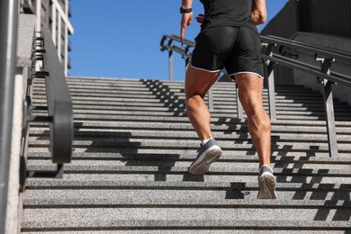 Photo of Man running up stairs outdoors on sunny day, closeup