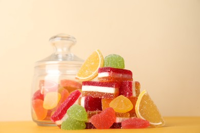 Pile of delicious bright jelly candies on yellow table