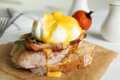 Photo of Delicious egg Benedict served on parchment, closeup