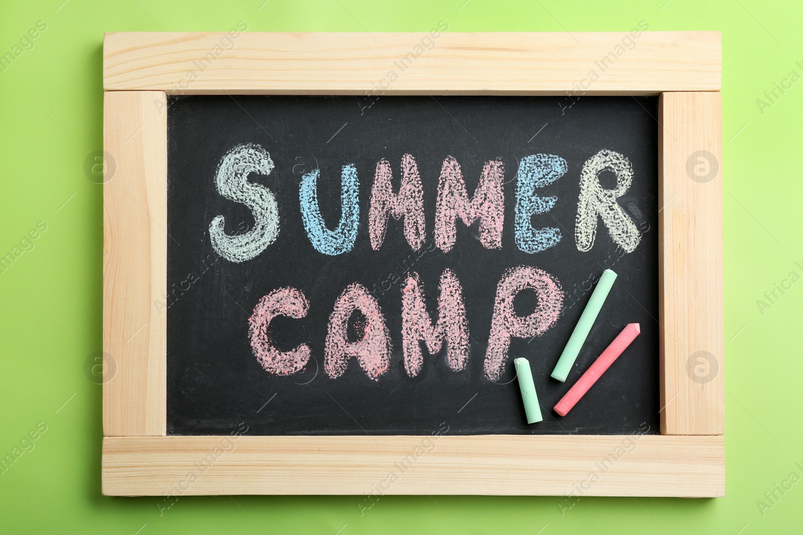 Photo of Text "SUMMER CAMP" on small blackboard and colorful chalk, top view