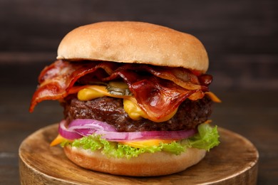 Photo of Tasty burger with bacon, vegetables and patty on wooden table, closeup