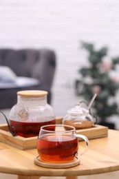 Photo of Teapot, cup of aromatic tea and sugar on wooden table indoors, space for text