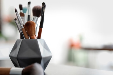 Holder with makeup brushes on table