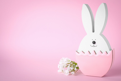 Easter bunny figure and flowers on pink background. Space for text