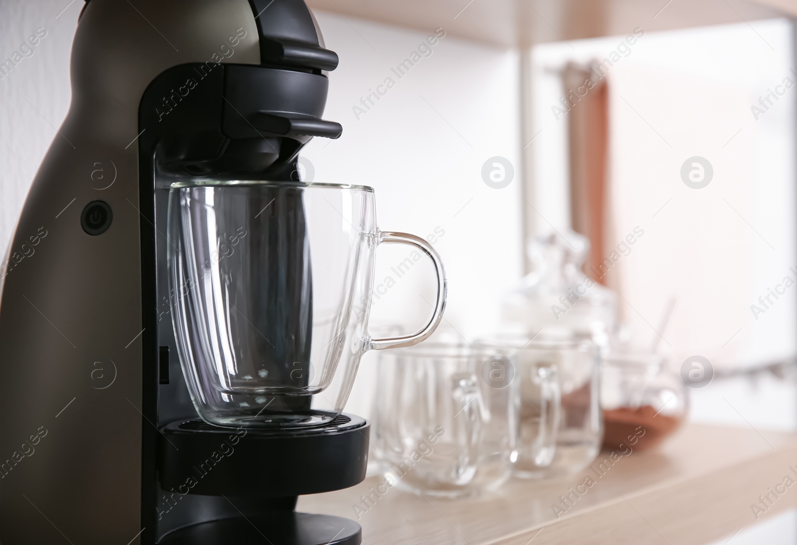 Photo of Modern coffeemaker with glass cup on wooden shelf, closeup